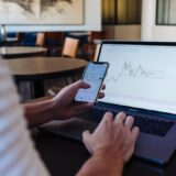 Personne utilisant un smartphone et un ordinateur pour illustrer DEGIRO et le courtage en ligne