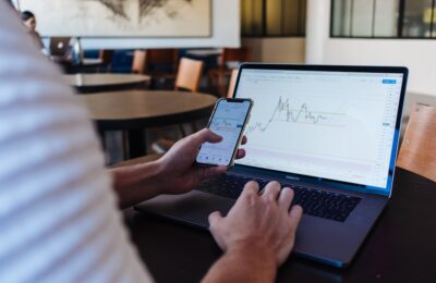 Personne utilisant un smartphone et un ordinateur pour illustrer DEGIRO et le courtage en ligne