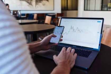 Personne utilisant un smartphone et un ordinateur pour illustrer DEGIRO et le courtage en ligne