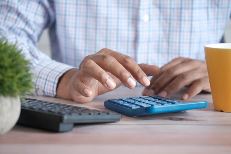 Main utilisant une calculatrice pour illustrer l’analyse d’une action à dividende