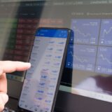 Smartphone et ordinateur affichant des graphiques financiers pour illustrer Trade Republic et l’investissement mobile