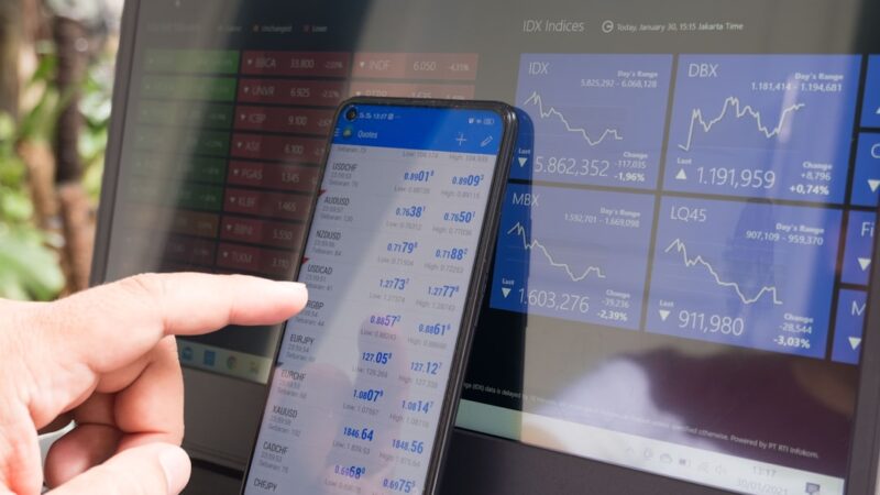 Smartphone et ordinateur affichant des graphiques financiers pour illustrer Trade Republic et l’investissement mobile